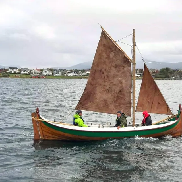 Liten seilskute med tre mennesker i på havet
