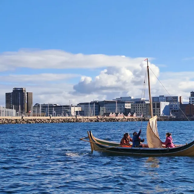 Liten seilskute med tre mennesker i på havet